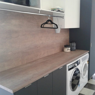 This is an example of a small contemporary single-wall separated utility room in Other with a built-in sink, flat-panel cabinets, grey cabinets, laminate countertops, brown walls, vinyl flooring, a side by side washer and dryer, multi-coloured floors and brown worktops.