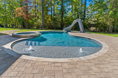 Example of a mid-sized classic backyard stone and kidney-shaped natural hot tub design in Raleigh