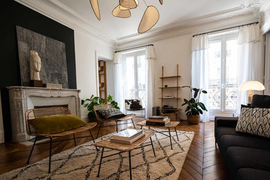 Cette image montre un grand salon design avec un mur blanc, un sol en bois brun, une cheminée standard, un manteau de cheminée en pierre et un sol marron.