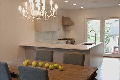 Eat-in kitchen - mid-sized transitional u-shaped light wood floor and beige floor eat-in kitchen idea in New York with an undermount sink, flat-panel cabinets, white cabinets, quartz countertops, white backsplash, mosaic tile backsplash, stainless steel appliances and a peninsula