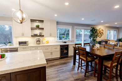 Large transitional u-shaped medium tone wood floor and gray floor open concept kitchen photo in San Francisco with an undermount sink, recessed-panel cabinets, white cabinets, quartz countertops, white backsplash, marble backsplash, stainless steel appliances, an island and white countertops