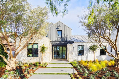 This is an example of a large country two-storey beige house exterior in Orange County with a gable roof, stone veneer and a metal roof.