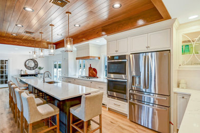 Example of a large transitional l-shaped vinyl floor and wood ceiling eat-in kitchen design in Other with a single-bowl sink, flat-panel cabinets, white cabinets, quartz countertops, white backsplash, ceramic backsplash, stainless steel appliances, an island and white countertops