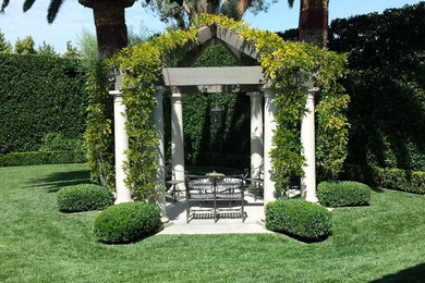 Photo of a mid-sized traditional partial sun backyard concrete paver formal garden in Los Angeles.