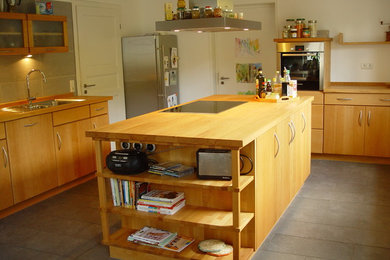 Mittelgroße Country Küche mit Einbauwaschbecken, Arbeitsplatte aus Holz, Küchenrückwand in Grau, Rückwand aus Porzellanfliesen, Küchengeräten aus Edelstahl, Zementfliesen für Boden, Kücheninsel und grauem Boden in Dortmund