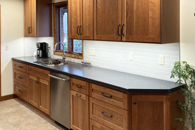 Kitchen - mid-sized transitional galley vinyl floor and beige floor kitchen idea in Other with an integrated sink, shaker cabinets, medium tone wood cabinets, laminate countertops, gray backsplash, subway tile backsplash, stainless steel appliances, no island and black countertops