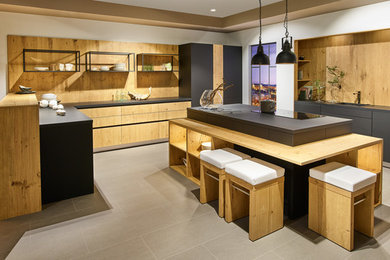 Design ideas for a large industrial u-shaped eat-in kitchen in Dresden with flat-panel cabinets, light wood cabinets, wood benchtops, brown splashback, timber splashback, with island and grey floor.