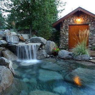 Réalisation d'un grand jardin arrière chalet avec une exposition ensoleillée, des pavés en pierre naturelle et une cascade.