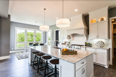 Mid-sized country single-wall open plan kitchen in Sacramento with an undermount sink, recessed-panel cabinets, white cabinets, granite benchtops, grey splashback, dark hardwood floors, with island, brown floor and beige benchtop.