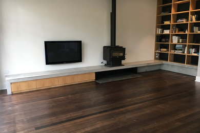Inspiration for a large contemporary open concept living room in Adelaide with white walls, dark hardwood floors, a wood stove, a metal fireplace surround and a wall-mounted tv.
