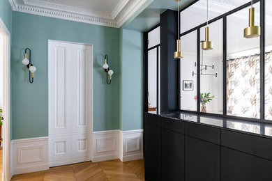 This is an example of a transitional entryway in Paris with blue walls, light hardwood floors and decorative wall panelling.