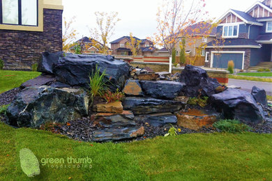 Design ideas for a rustic full sun front yard stone water fountain landscape in Edmonton for summer.