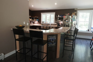 Inspiration for a mid-sized industrial l-shaped dark wood floor and brown floor open concept kitchen remodel in Boston with a farmhouse sink, shaker cabinets, dark wood cabinets, granite countertops, beige backsplash, stone slab backsplash, stainless steel appliances, a peninsula and beige countertops
