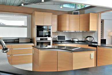 Inspiration for a large contemporary u-shaped limestone floor and beige floor eat-in kitchen remodel in Tampa with flat-panel cabinets, light wood cabinets, granite countertops, white backsplash, glass tile backsplash, stainless steel appliances and an island