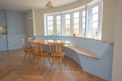 Inspiration for a large country kitchen/diner in Sussex with an integrated sink, shaker cabinets, blue cabinets, composite countertops, beige splashback, ceramic splashback, integrated appliances, medium hardwood flooring, an island, brown floors and beige worktops.