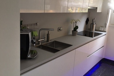 This is an example of a large contemporary galley kitchen in Other with a drop-in sink, flat-panel cabinets, white cabinets, stainless steel appliances, porcelain floors and multi-coloured floor.