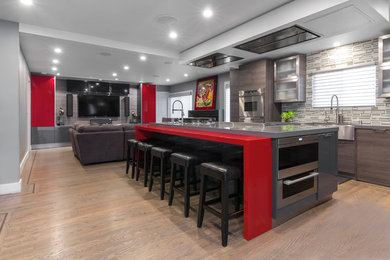 Example of a mid-sized trendy l-shaped light wood floor open concept kitchen design in San Francisco with a farmhouse sink, flat-panel cabinets, gray cabinets, quartz countertops, multicolored backsplash, glass tile backsplash, stainless steel appliances and an island