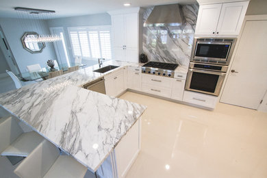 Photo of a large contemporary l-shaped separate kitchen in Miami with an undermount sink, shaker cabinets, white cabinets, marble benchtops, red splashback, marble splashback, stainless steel appliances, porcelain floors, a peninsula, beige floor and white benchtop.