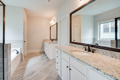 This is an example of a mid-sized transitional master wet room bathroom in Other with recessed-panel cabinets, white cabinets, a drop-in tub, gray tile, porcelain tile, grey walls, porcelain floors, an undermount sink, granite benchtops, grey floor and a hinged shower door.