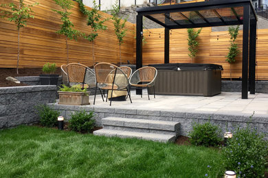 Photo of a mid-sized modern full sun hillside concrete paver and wood fence retaining wall landscape in Vancouver for spring.