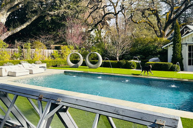 Ejemplo de piscina natural clásica grande rectangular en patio trasero con adoquines de piedra natural
