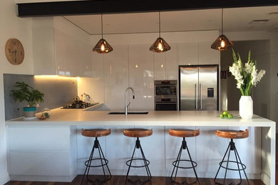 Large contemporary u-shaped eat-in kitchen in Melbourne with marble benchtops and stainless steel appliances.