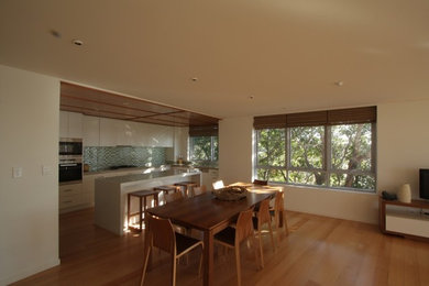 Photo of a large beach style open plan dining in Brisbane with light hardwood floors and white walls.