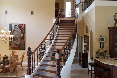 Large tuscan wooden curved open and mixed material railing staircase photo in Miami