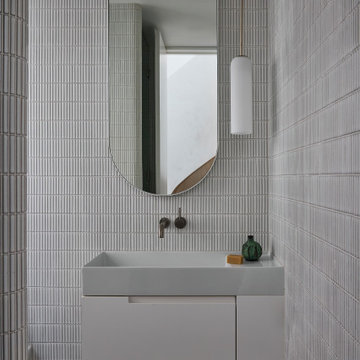 Powder Room with Vertical Tiles and Arched Mirror