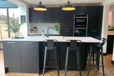 Large contemporary open plan kitchen in Other with flat-panel cabinets, black cabinets, quartz worktops, white splashback, ceramic splashback, stainless steel appliances, an island, white worktops and feature lighting.