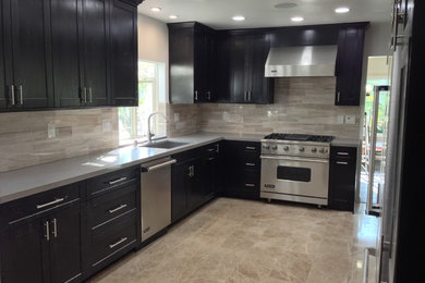 Mid-sized transitional l-shaped travertine floor enclosed kitchen photo in Los Angeles with an undermount sink, shaker cabinets, dark wood cabinets, quartz countertops, beige backsplash, stone tile backsplash, stainless steel appliances and no island