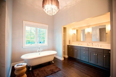 Inspiration for a large transitional master dark wood floor and brown floor claw-foot bathtub remodel in Chicago with shaker cabinets, dark wood cabinets, gray walls, an undermount sink, quartz countertops and white countertops