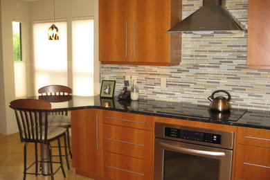 Open concept kitchen - mid-sized contemporary galley porcelain tile open concept kitchen idea in Austin with an undermount sink, medium tone wood cabinets, granite countertops, multicolored backsplash, matchstick tile backsplash and stainless steel appliances