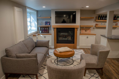Mid-sized elegant underground vinyl floor and brown floor basement photo in Minneapolis with a bar, gray walls, a standard fireplace and a wood fireplace surround