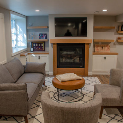 Mid-sized elegant underground vinyl floor and brown floor basement photo in Minneapolis with a bar, gray walls, a standard fireplace and a wood fireplace surround