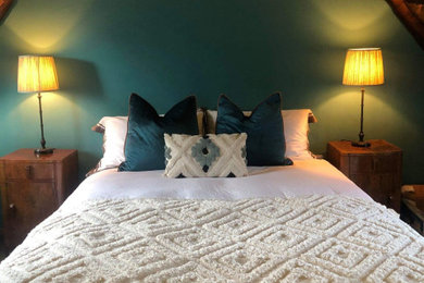 オックスフォードシャーにある小さなトラディショナルスタイルのおしゃれな客用寝室 (緑の壁、無垢フローリング、茶色い床、表し梁)