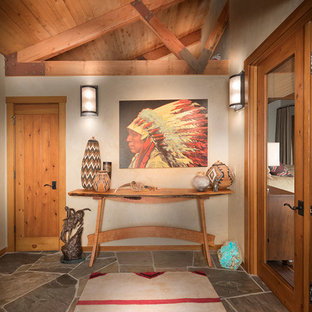 Réalisation d'un hall d'entrée bohème de taille moyenne avec un mur beige, un sol en ardoise, une porte en bois brun et un sol gris.