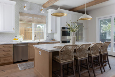 Example of a mid-sized transitional l-shaped light wood floor and exposed beam open concept kitchen design in Sacramento with a drop-in sink, shaker cabinets, white backsplash, porcelain backsplash, stainless steel appliances, an island and white countertops