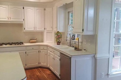 Design ideas for a mid-sized traditional l-shaped eat-in kitchen in Other with a drop-in sink, raised-panel cabinets, white cabinets, white appliances, medium hardwood floors and with island.