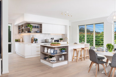 Inspiration for a large contemporary l-shaped open plan kitchen in Other with an integrated sink, shaker cabinets, white cabinets, quartz benchtops, grey splashback, ceramic splashback, panelled appliances, light hardwood floors, with island, beige floor and white benchtop.