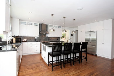 Example of a mid-sized transitional l-shaped medium tone wood floor and brown floor eat-in kitchen design in Toronto with an undermount sink, white cabinets, gray backsplash, stone tile backsplash, stainless steel appliances, an island, shaker cabinets and quartz countertops