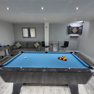 Immagine di un piccolo soggiorno minimalista chiuso con sala giochi, pareti grigie, pavimento in laminato, TV a parete e pavimento grigio