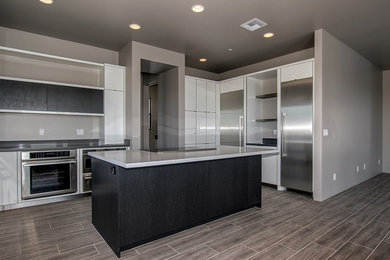 This is an example of a large contemporary eat-in kitchen in Phoenix with an undermount sink, flat-panel cabinets, white cabinets, quartz benchtops, stainless steel appliances, porcelain floors, with island and brown floor.