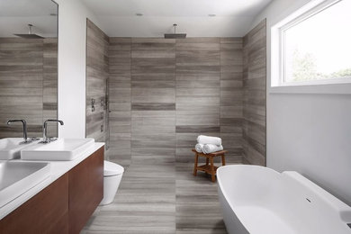 Large trendy master gray tile and ceramic tile ceramic tile bathroom photo in Toronto with flat-panel cabinets, medium tone wood cabinets, a one-piece toilet, white walls, a vessel sink and quartz countertops