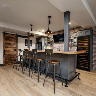 フィラデルフィアの大きいインダストリアルスタイルのおしゃれな着席型バー (アンダーカウンターシンク、シェーカースタイル扉のキャビネット、グレーのキャビネット、木材カウンター、マルチカラーのキッチンパネル、レンガのキッチンパネル、クッションフロア、ベージュの床、ベージュのキッチンカウンター) の写真