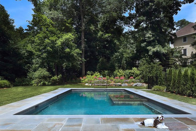 Large traditional backyard pool in New York with natural stone pavers.