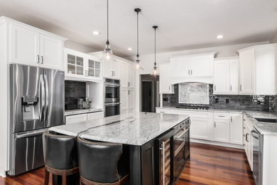 Example of a large transitional u-shaped eat-in kitchen design in Columbus with white cabinets, granite countertops and an island