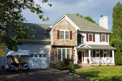 This is an example of a mid-sized traditional concrete paver front porch design in Huntington with a roof extension.