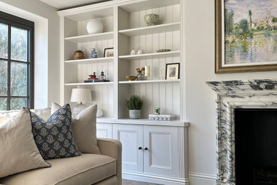 Inspiration for a classic cream and black living room in Surrey with beige walls, light hardwood flooring, a standard fireplace, a stone fireplace surround, a concealed tv and brown floors.