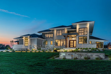 Inspiration for a large modern gray two-story stone house exterior remodel in Columbus with a hip roof and a shingle roof